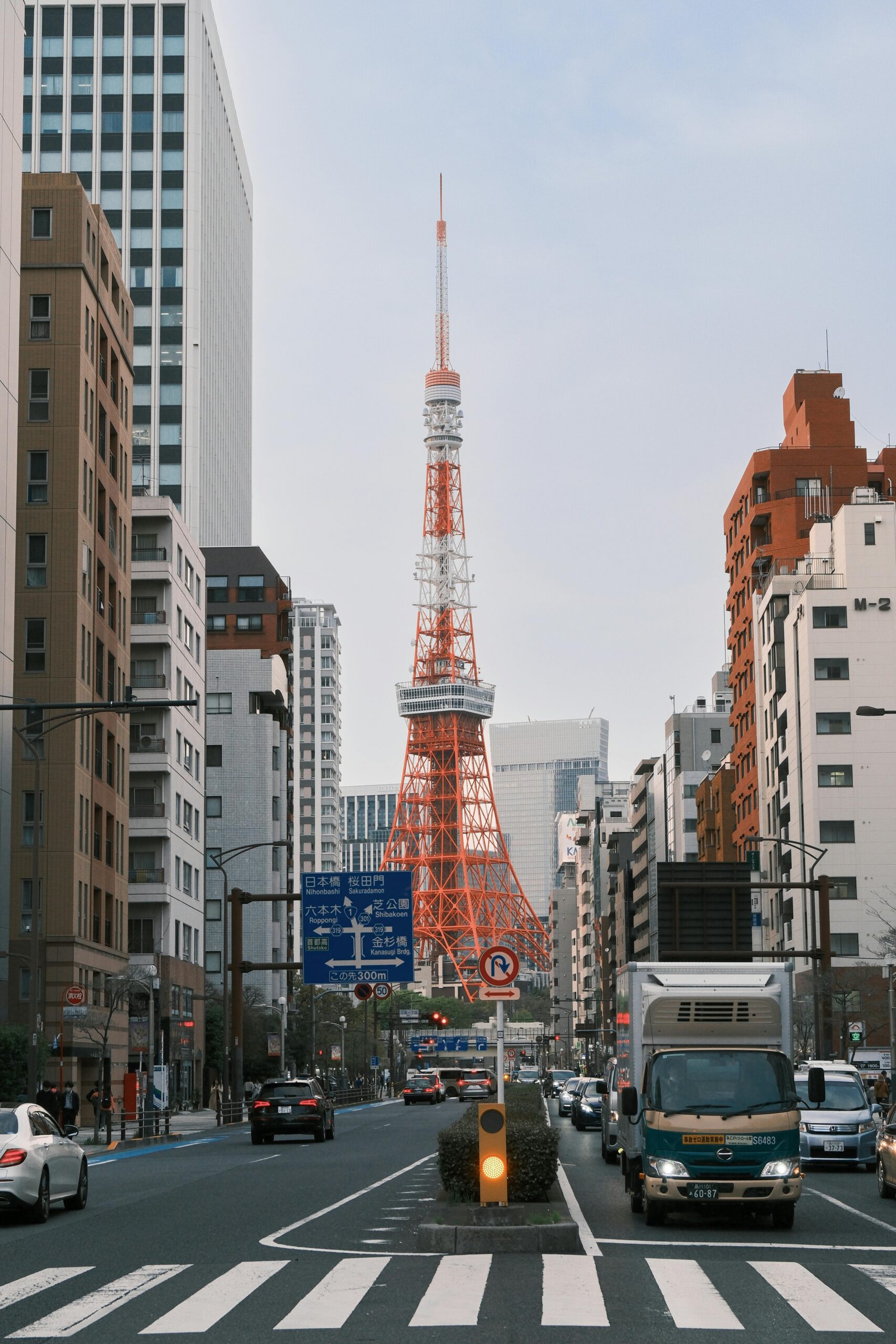 A cityscape featuring Tokyo Tower, captured from street level in busy Tokyo, Japan.