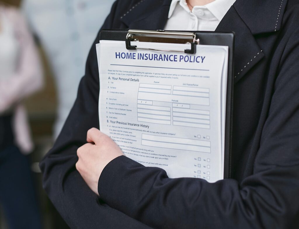 pexels-photo-7734672-7734672 Close-up of a person holding a home insurance policy on a clipboard, captured indoors.
